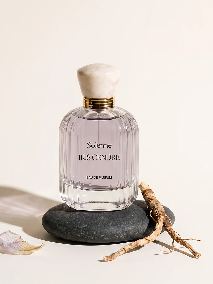 Iris Cendr&eacute; eau de parfum on a dark stone beside an iris root.